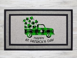 Mockup of a St. Patrick's Day themed welcome mat featuring a green buffalo plaid farm truck with shamrocks in the back and the phrase, "Happy St. Patrick's Day" underneath it