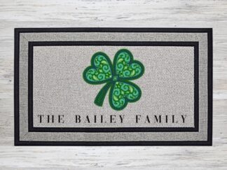 Mockup of a custom welcome doormat that features your last name under a large mandala shamrock.