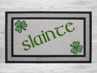 Mockup of a saint patrick's day themed doormat featuring the saying, "slainte" with two mandala styled shamrocks in the corners.