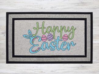 Mockup of an Easter themed doormat that features the phrase "Happy Easter" with a trio of dyed & decorated Easter eggs and bunny ears on the 'E' of the word Easter