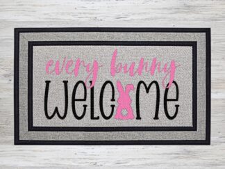 Mockup of an Easter themed doormat that features the phrase "Every Bunny Welcome" with an adorable pink Bunny