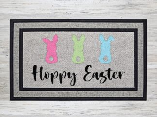 Mockup of an Easter themed doormat that features the phrase "Happy Easter" with a trio of cute pastel bunnies