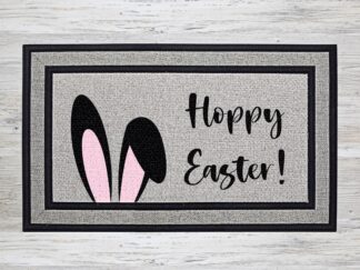 Mockup of an Easter themed doormat that features the phrase "Hoppy Easter" with an oversized floppy pair of bunny ears