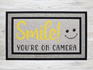 Mock up of doormat that reads, "Smile! You're on Camera"