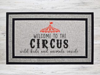 Mockup up a funny welcome mat featuring the saying, "Welcome to the circus, wild kids and animals inside" with a red circus tent image and a fun black font