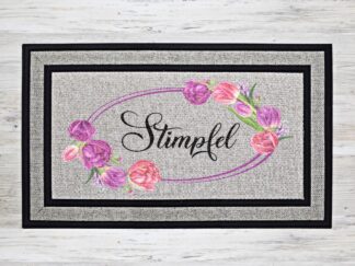 Mockup of a custom welcome doormat that features your last name in a wreath of purple and pink blossoms.