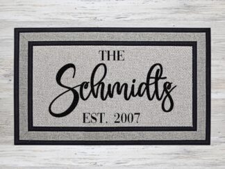 Mockup of a personalized doormat that features your family's last name in a bold modern script with the year the family was established underneath.
