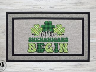 Mockup of a saint patrick's day themed doormat featuring the saying, "Let the Shenanigans Begin" with a trio of shamrocks