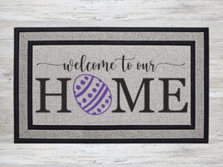 Mockup of an Easter themed doormat that features the phrase "Welcome to our Home" with a dyed & decorated Easter egg in place of the 'O' in the word Home