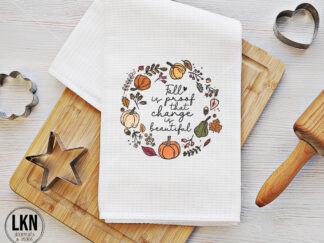 White dish towel with black text 'Fall is proof that change is beautiful'.