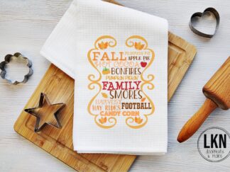 Fall dish towel with decorative word art listing autumn activities and treats