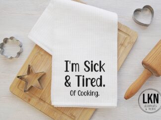White dish towel with black text 'I'm sick and tired. Of cooking.'