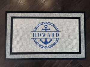 Blue rope encircles an anchor with last name on a doormat, creating a nautical theme for a personalized touch.