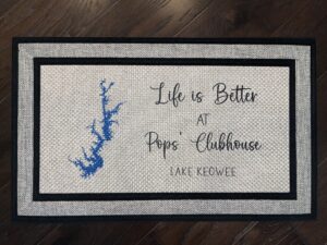 Photo of a doormat for a client father at Lake Keowee in South Carolina, that says "Life is Better at Pops' Clubhouse, Lake Keowee" with a cartography map of Lake Keowee.