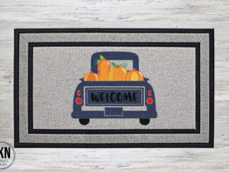 Mockup of a doormat featuring a blue vintage farm truck with pumpkins in the bed and welcome written across the back
