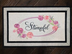 Custom doormat with a family last name in a wreath of purple and pink blossoms