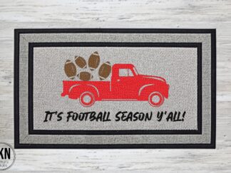 Mockup of a football themed doormat that reads, "It's Football Season Y'all" with a large red vintage style pickup truck with footballs in the back