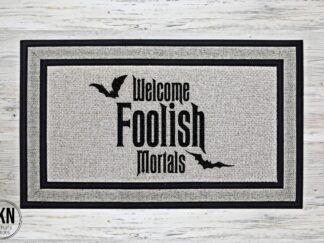 Mockup of a Halloween themed doormat featuring the phrase Welcome Foolish Mortals