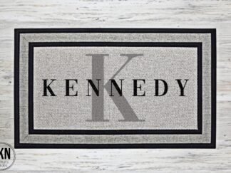 Mockup of a doormat featuring the family's last name in a bold black and the family's monogram behind in gray.