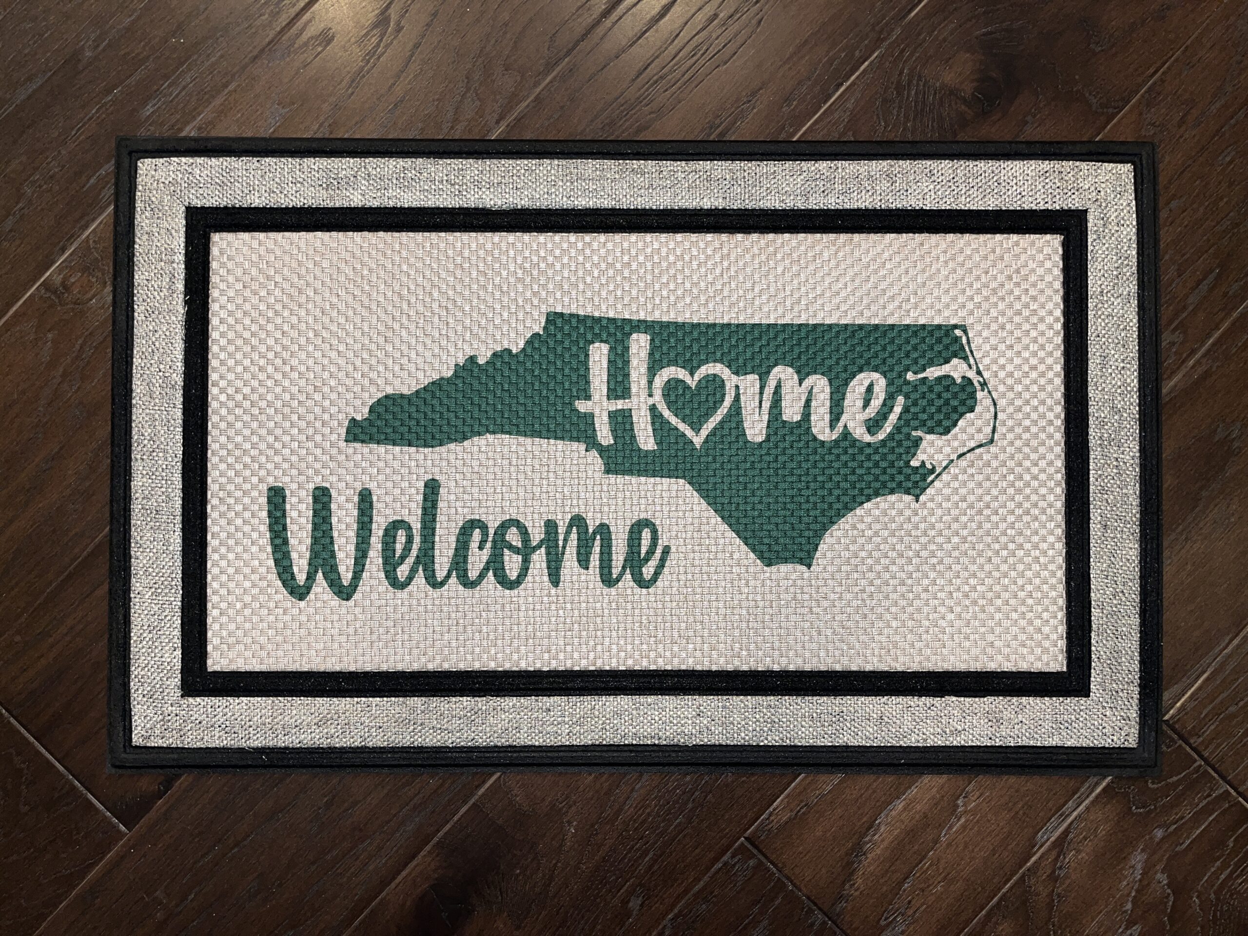 Custom doormat requested by a client that reads Welcome Home, within a silhouette of the state of North Carolina